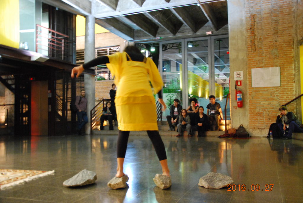 Tentativa#2. Performance duracional. Ações movidas: carregar as pedras, andando nelas. Tricotar com olhos fechados.  Ação realizada no TUCARENA, SP, Brasil, durante a Semana das Artes do Corpo (2017). Foto: Bianca Hisse